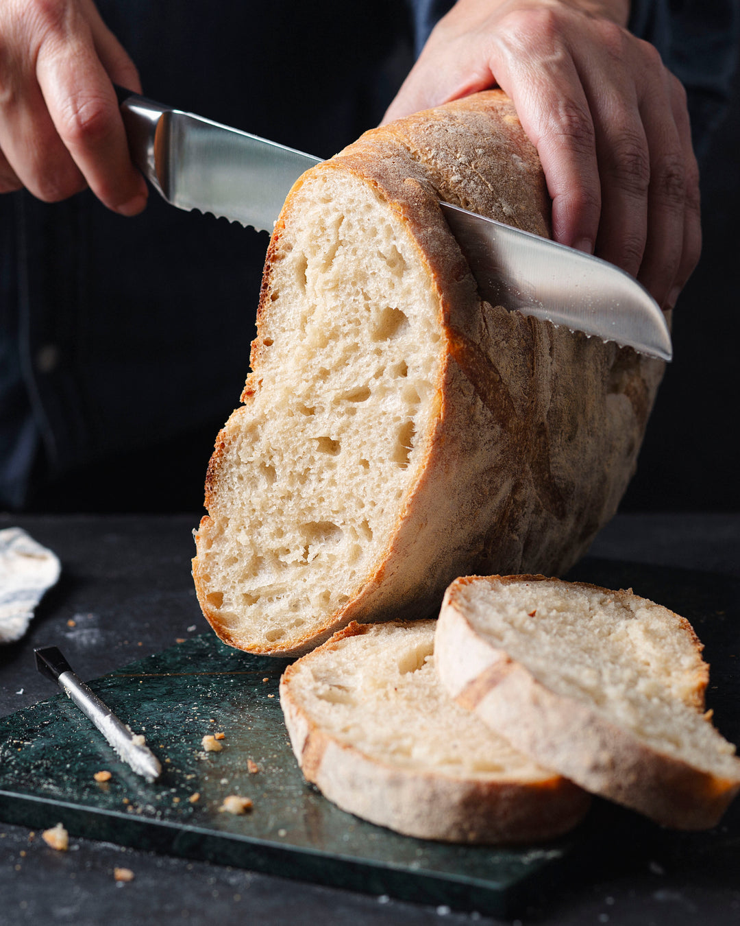 A person cutting sourdough bread with knife